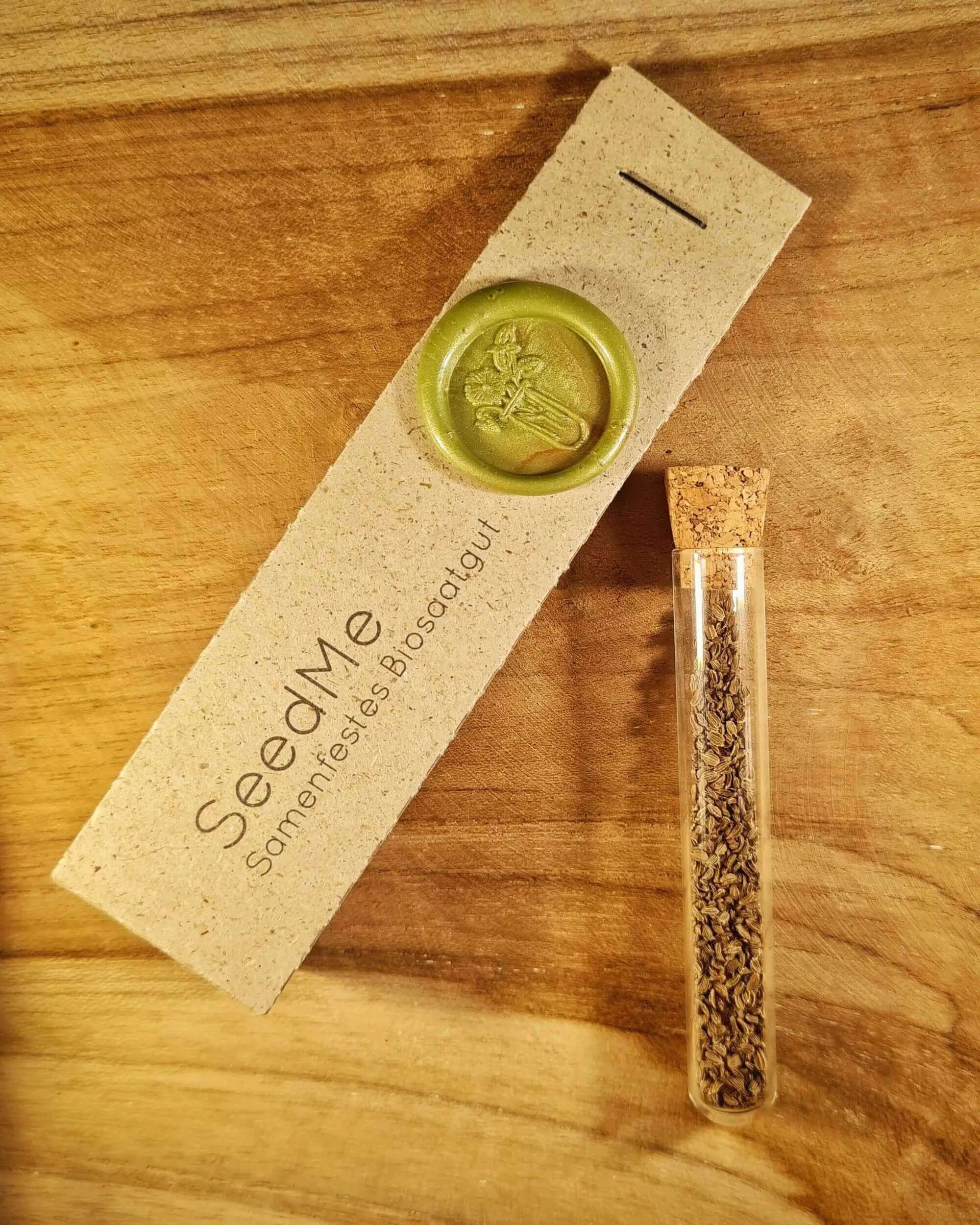 Samen für lila Möhre im Reagenzglas, daneben eine Graspapierverpackung von SeedMe