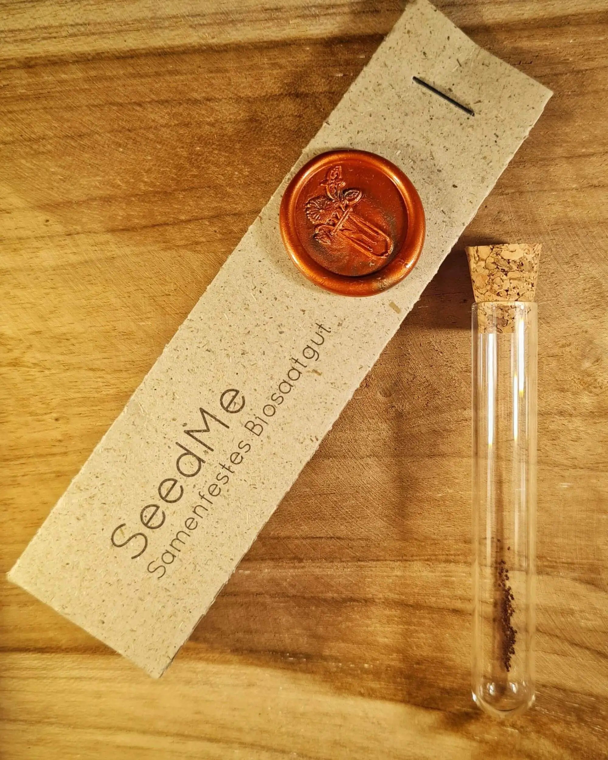 Samen für Oregano &quot;Griechischer im Reagenzglas und daneben eine Graspapierverpackung von SeedMe mit buntem Wachssiegel